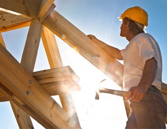 ouvrier charpentier debout sur la structure de la toiture qu'il à construit
